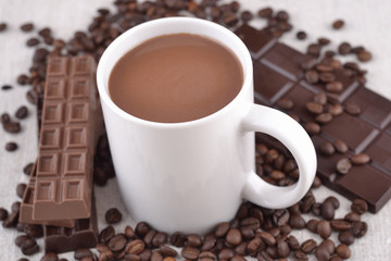 White cup of hot chocolate on coffee beans and chocolate backgro