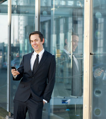 Happy business man smiling outdoors with cellphone