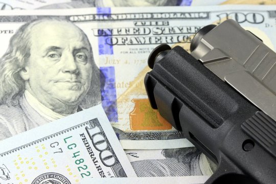 Hand Gun with American Currency - Financial Security