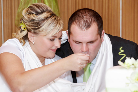 bride feeding her groom with spoon on wedding lunch