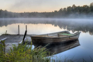 Foto auf Leinwand Ein schmutziges Boot an einem Holzsteg © dfaagaard