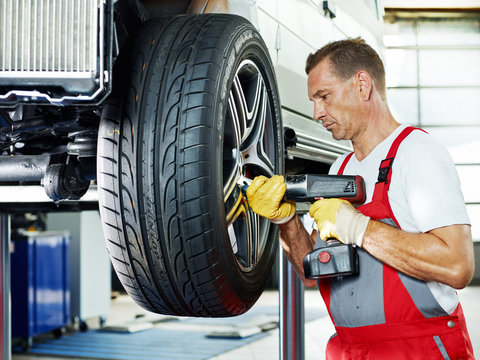 Motor mechanic is changing a tyre with new alu rim