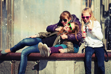 Teenage girls relaxing against a city fountain