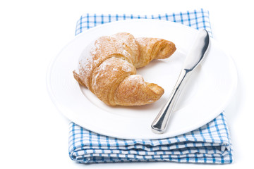 fresh croissant and a knife on a plate isolated