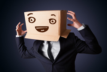 Businessman gesturing with a cardboard box on his head with smil