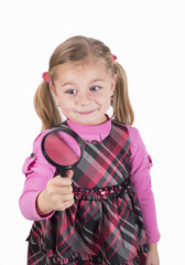 Little girl looking through a magnifying glass carefully.