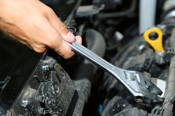 Hand with wrench. Auto mechanic in car repair