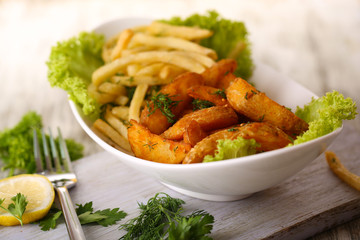 French fries and home potatoes on plate on board on wooden
