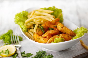 French fries and home potatoes on plate on board on wooden