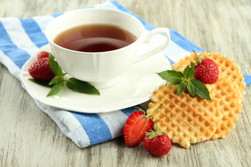 Cup of tea with cookies and strawberries on table close-up