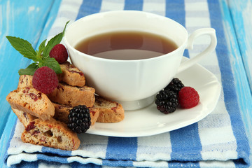 Cup of tea with cookies and berries on table close-up