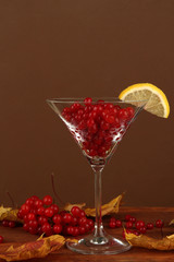 Red berries of viburnum in glass and yellow leaves