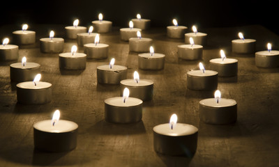 Many burning candles on a wooden table