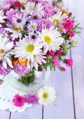 Obraz na płótnie Canvas Polne kwiaty w szklanym wazonie na serwetce na drewnianym stole