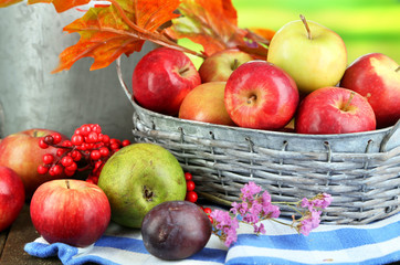 Juicy apples in basket on table on natural background