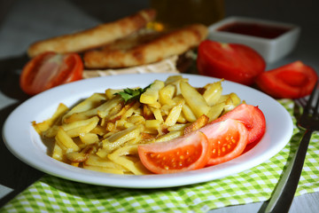 Ruddy fried potatoes on plate on wooden table close-up