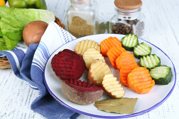 Beautiful sliced vegetables, on plate, on wooden background