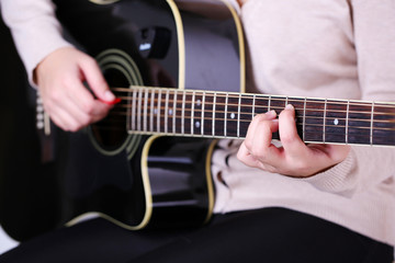 Fototapeta na wymiar Gitara akustyczna w rękach kobiet, zbliżenie