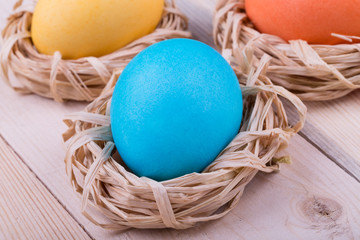 Easter eggs in small nests on wooden background