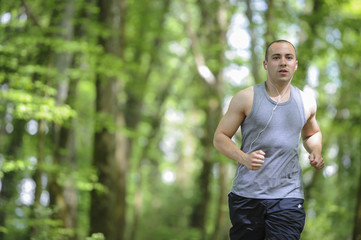Naklejka na ściany i meble Young man running in the woods listening music