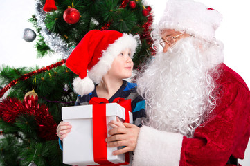 Fototapeta na wymiar Old Santa Clause and young little boy holding gift box together