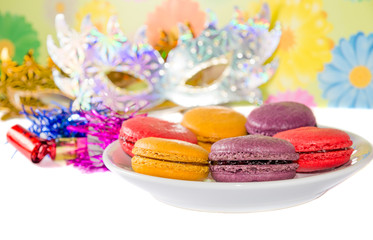 Sweet colorful macaron against festive masks and pipes