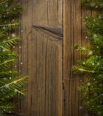 Spruce twigs with falling snow on wooden background