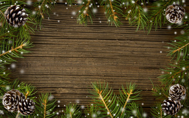 Spruce twigs and cones with falling snow on wooden background