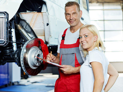 Customer and mechanic in a garage look at a quotation