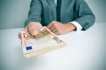 man in suit with a wad of euro bills