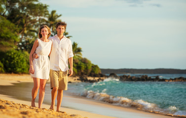 Young couple in love walking on the beach at sunset