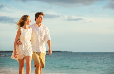 Young couple in love walking on the beach at sunset