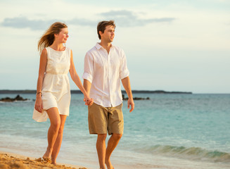 Young couple in love walking on the beach at sunset