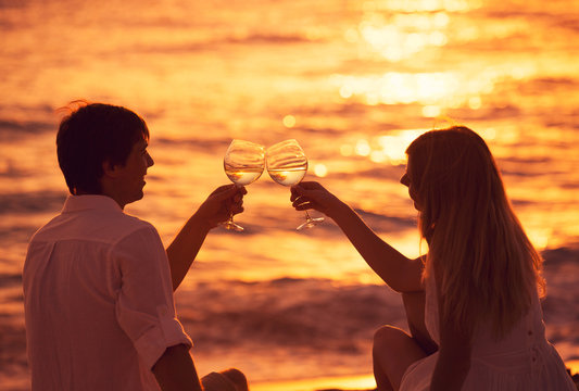 Silhouette of couple enjoying glass of champagne on tropical bea