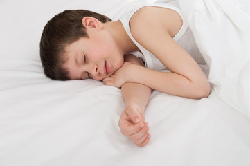 Obraz na płótnie Canvas cheerful boy sleep in white bed