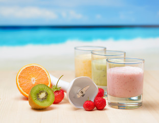 Fruit smoothie on wooden table on tropical beach