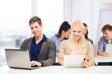 two smiling students with laptop and tablet pc