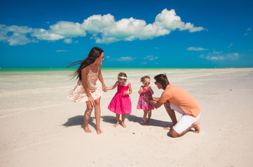 Fototapeta premium Young beautiful family with two daughters having fun at beach