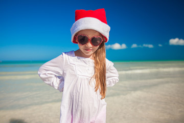 Little girl in red hat santa claus and sunglasses on the exotic