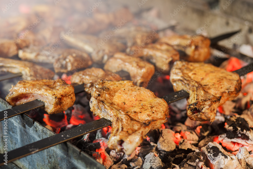 Wall mural Appetizing steaks prepared on a grill wood coal, outdoor