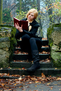 Fototapeta Beautiful girl reading a book on the stairs