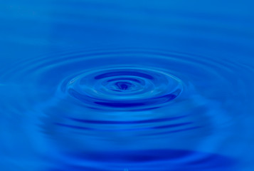 A drop of water falling in blue water