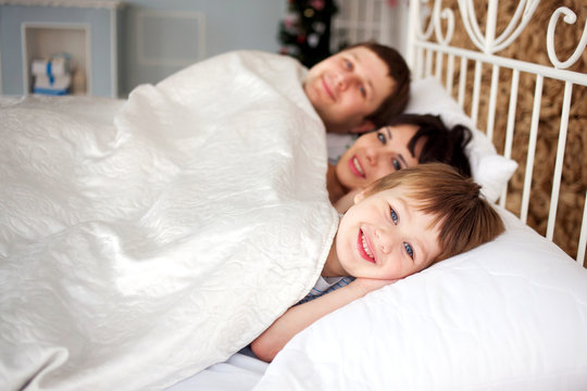 Happy family lying in bed, family concept.
