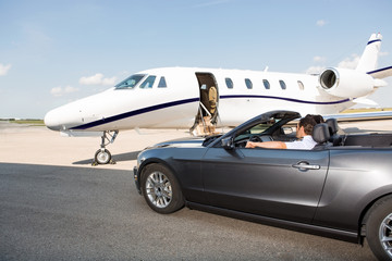 Pilot In Convertible Parked Against Private Jet