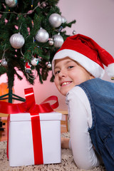 Happy little girl smiling with gift box near the Christmas tree.