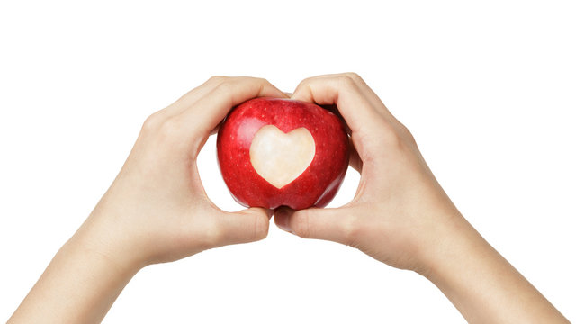 female teen hands holding apple with carved heart