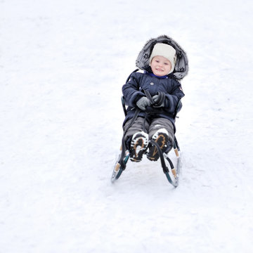 Boy sliding on snow - outdoors