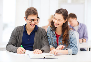 two teenagers with notebooks and book at school