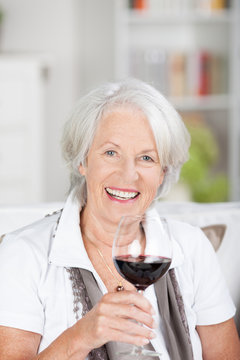 lächelnde seniorin genießt ein glas rotwein