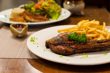 Pork Chop Grilled steak with French Fries, top with parsley.